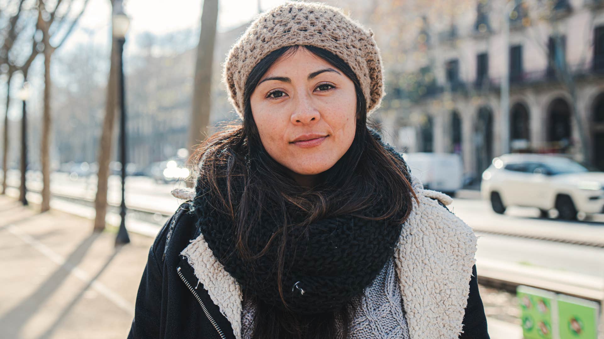 front view of young woman looking pensive at camera with coat and hat. 