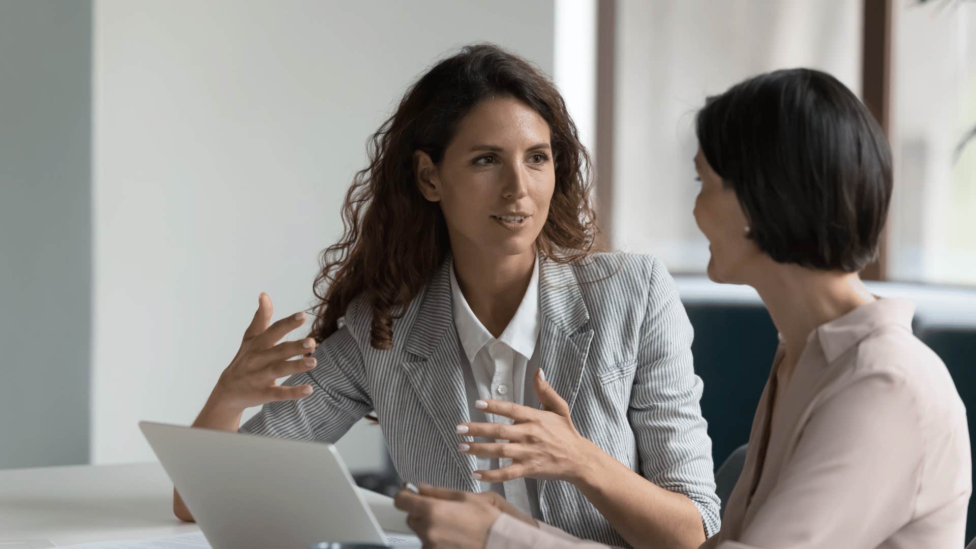 woman talking to another woman in front of a laptop