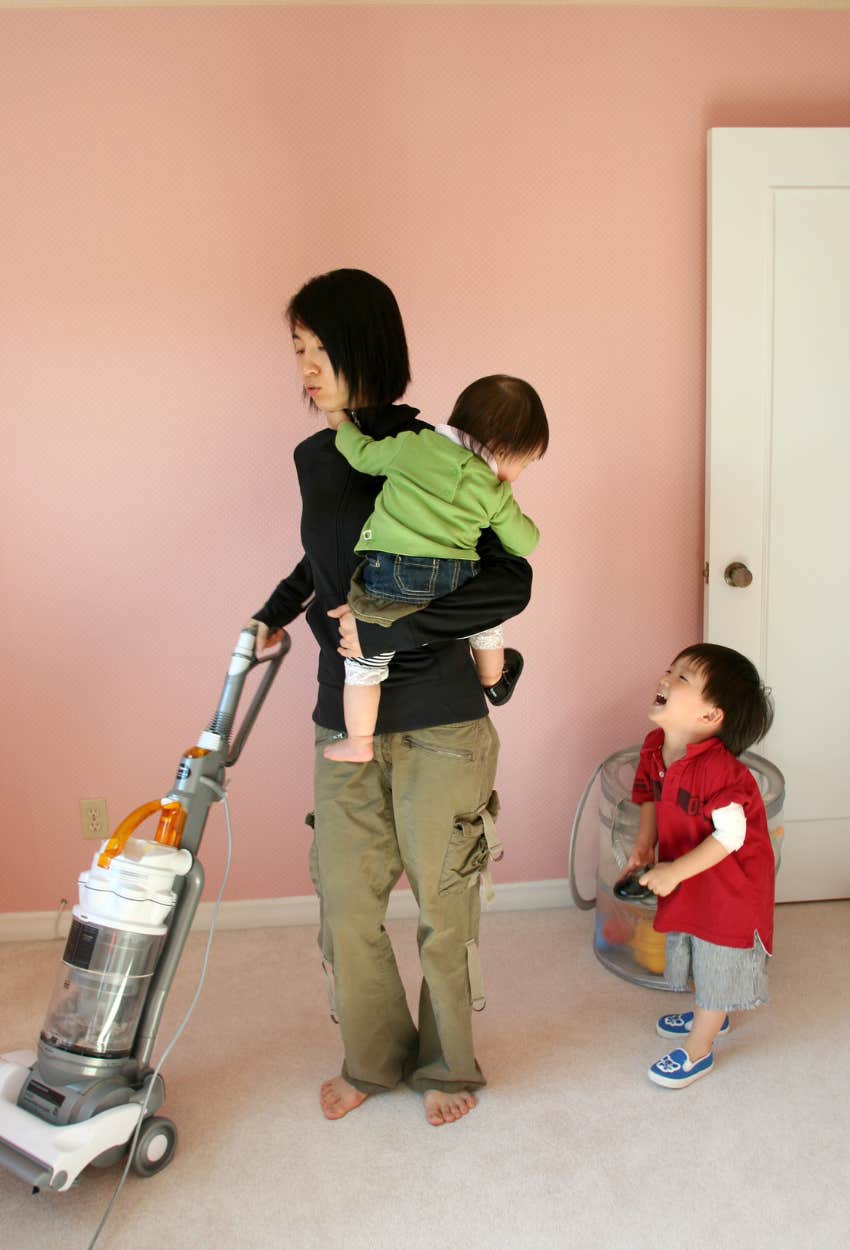 mom doing housework while caring for two young children