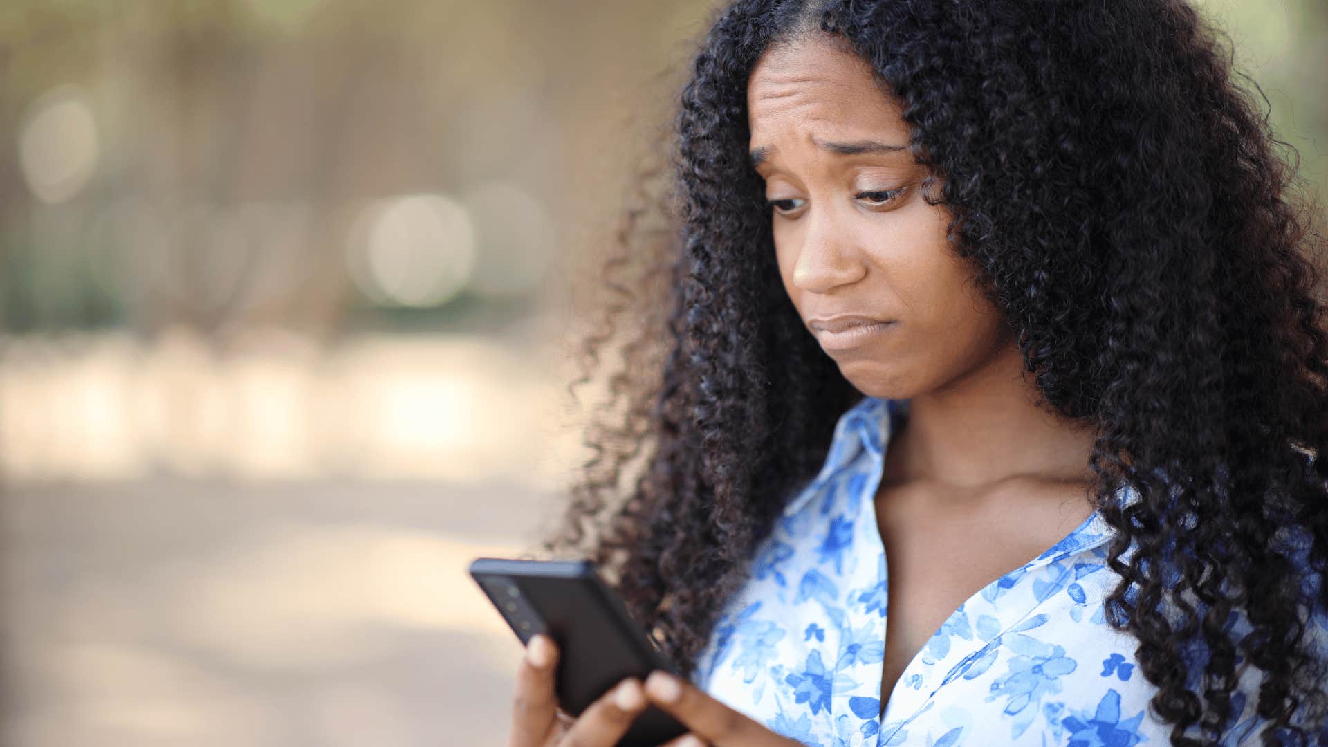 Woman looks at mobile phone and is perplexed