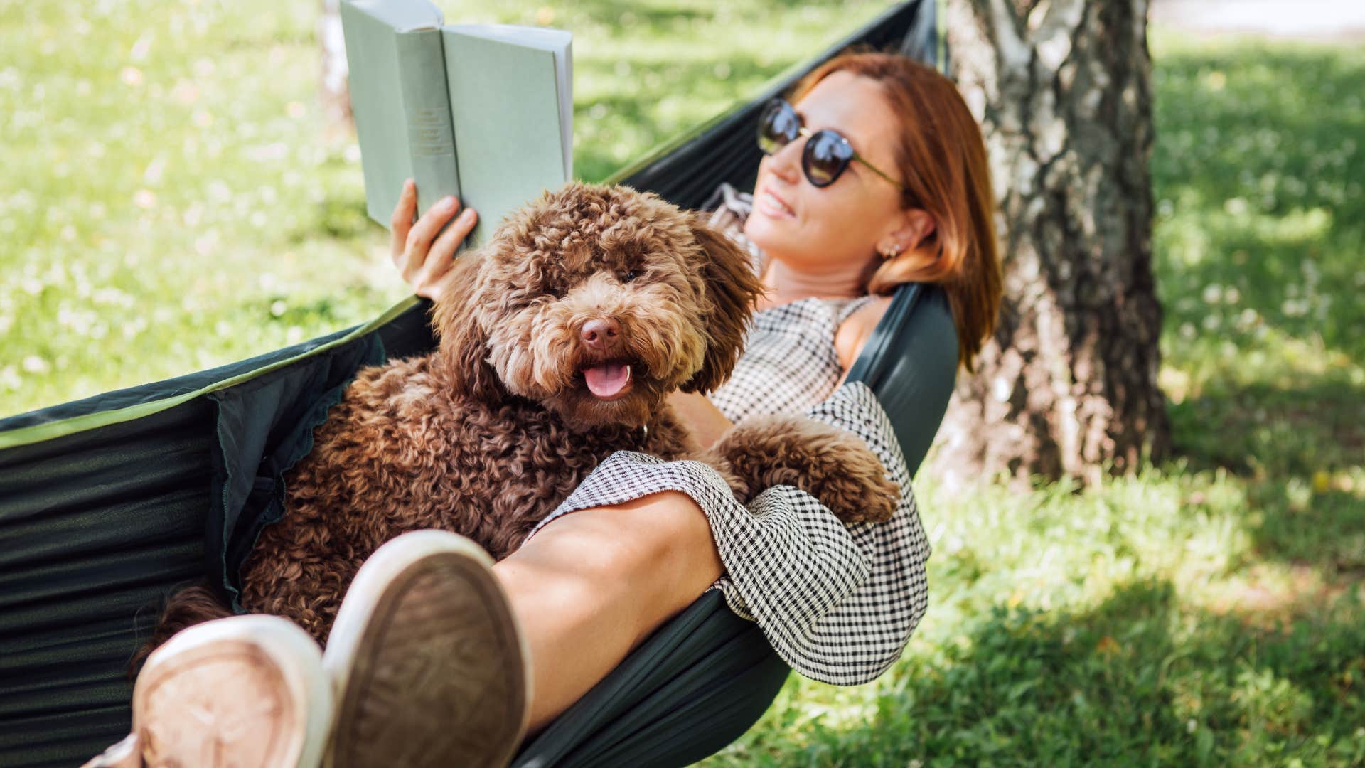 woman contentedly swinging in a hammock with her dog