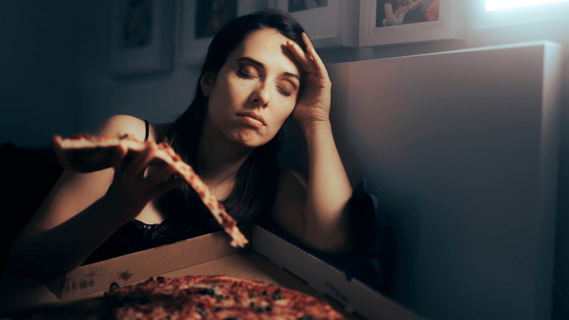 Stressed Tired Woman Having a Slice of Pizza at Night.