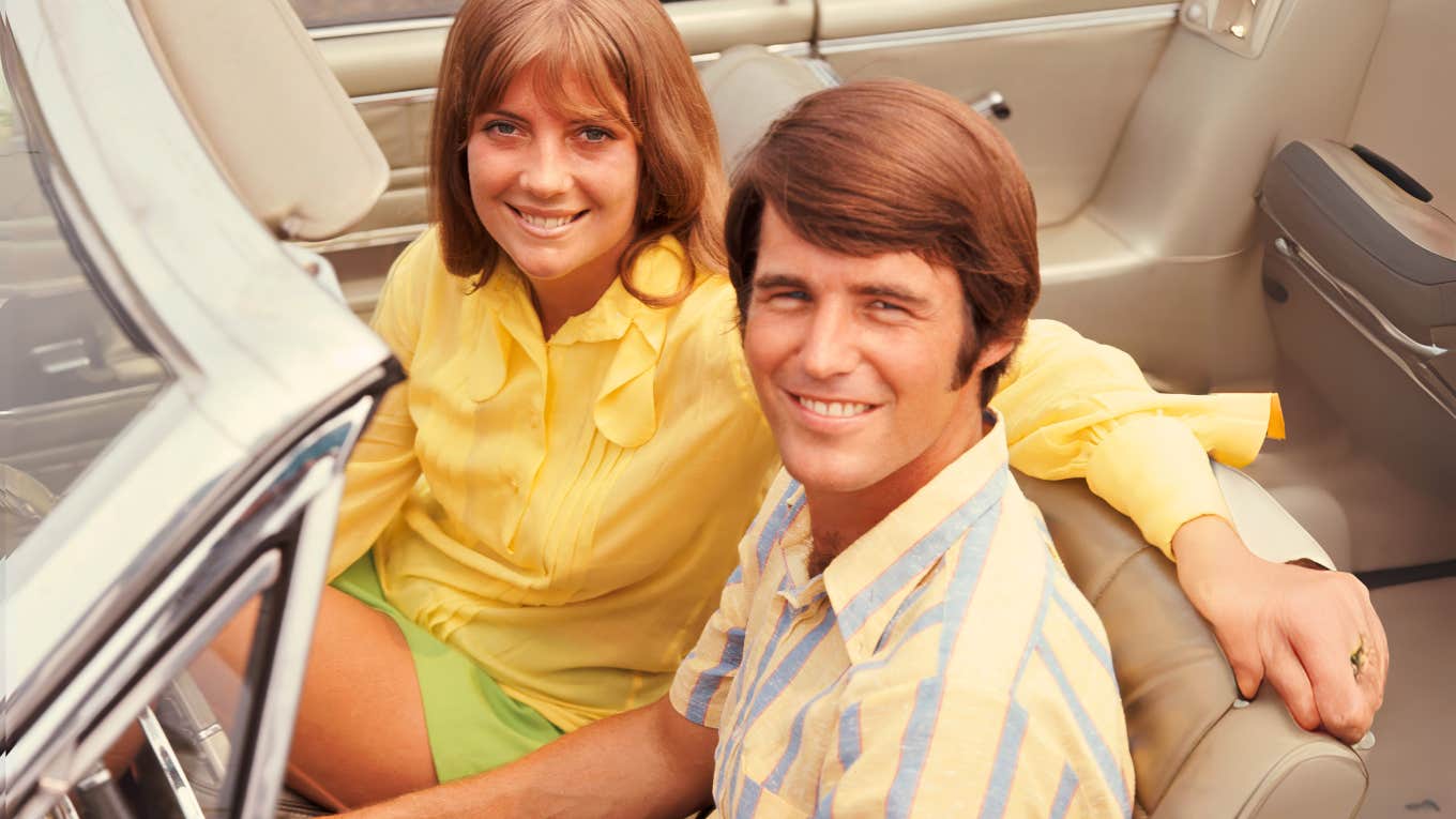 Baby boomer couple in the 70's sitting in car. 