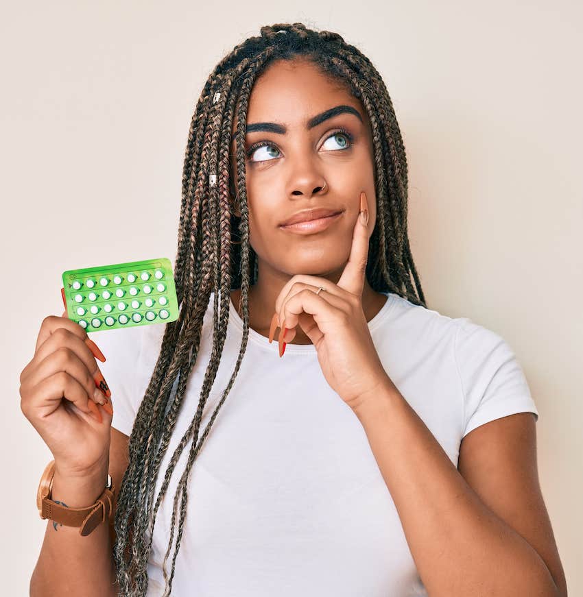 Woman holding brith control pills packet and wondering about her uncontrollable emotions 