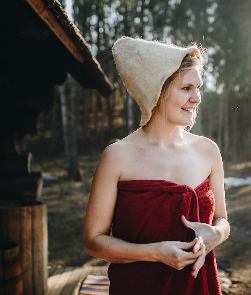 Relaxed woman stands outside sauna