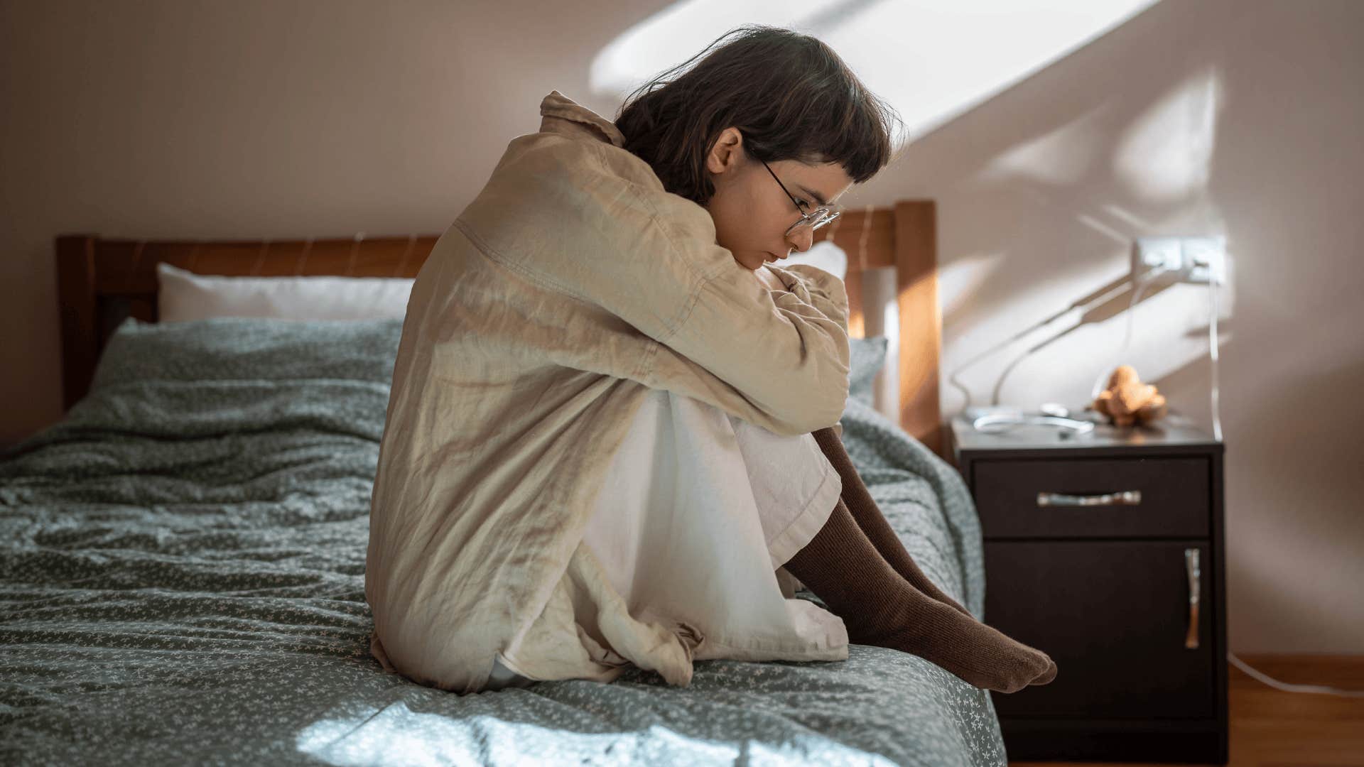 emotional unsociable woman sitting on bed