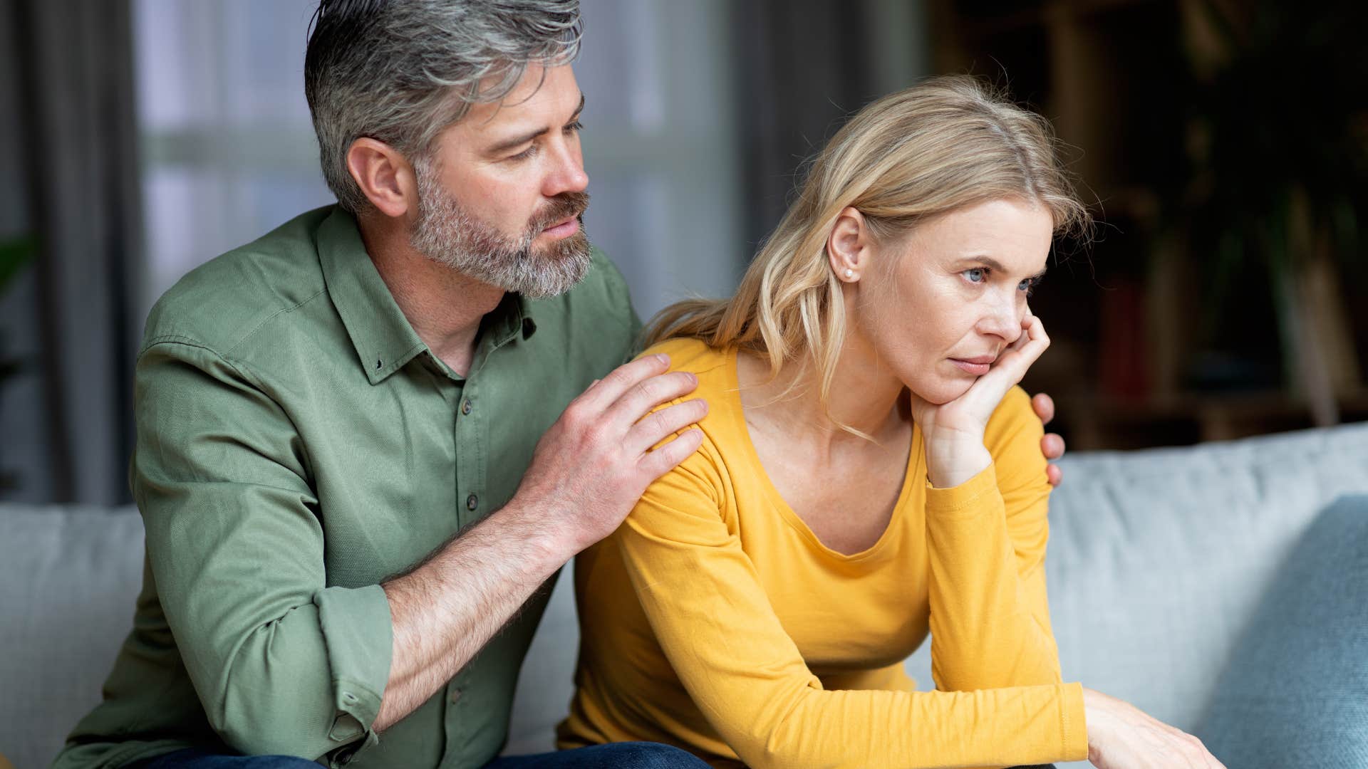 Man comforting his upset wife on a couch