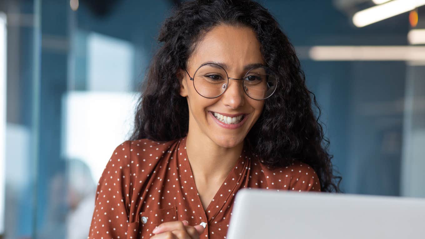 Confident woman smiling and talking to someone on her laptop.