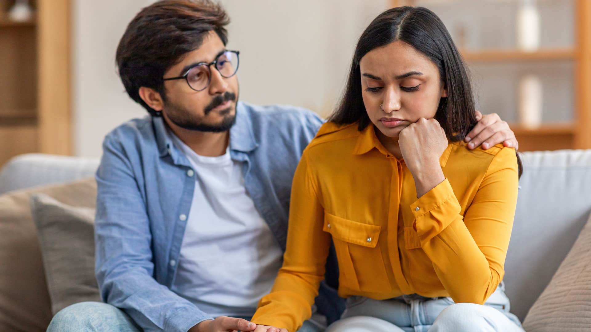 Man comforting his upset wife on the couch