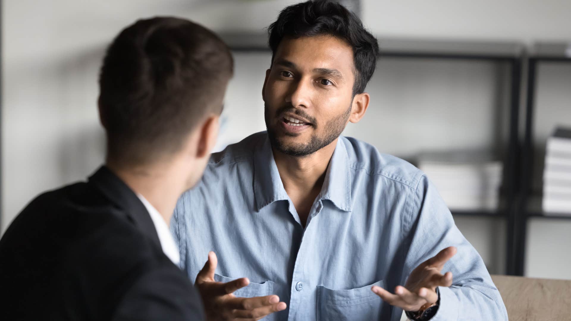 Man talking to a co-worker at a desk.