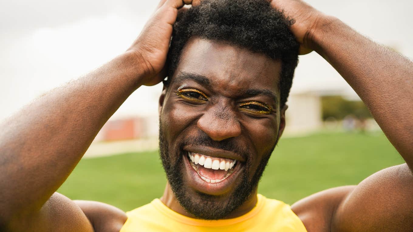 A man with a life filled with joy, wearing a yellow tank and smiling big