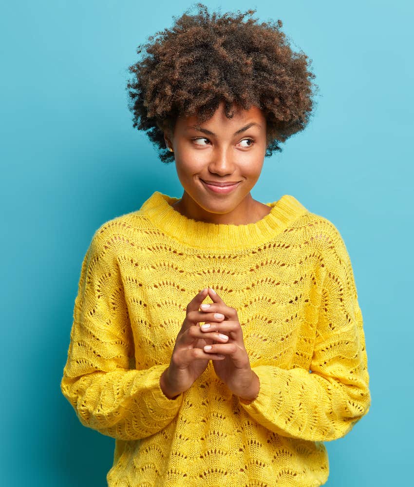 Excited woman holds hands together, rewriting the story she tells herself for more joy 