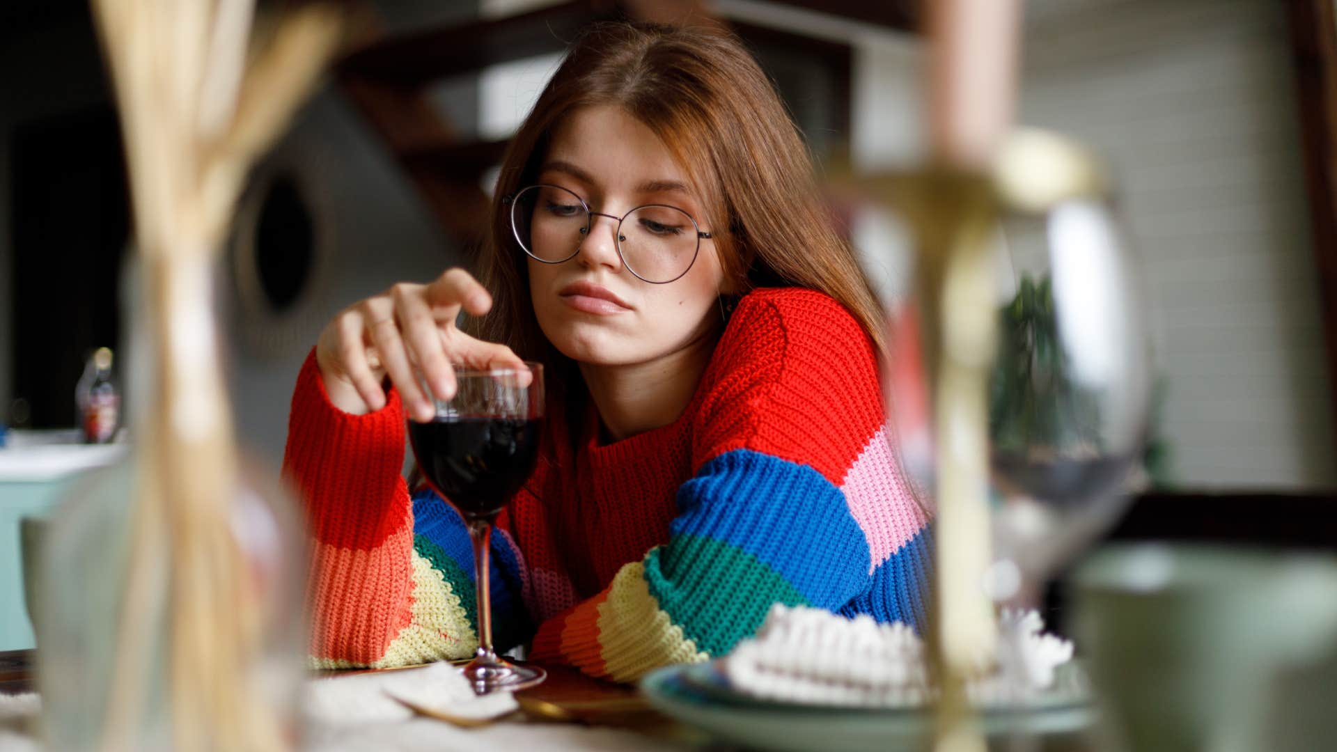 Sad young woman with a glass of wine sits at the table on a date.