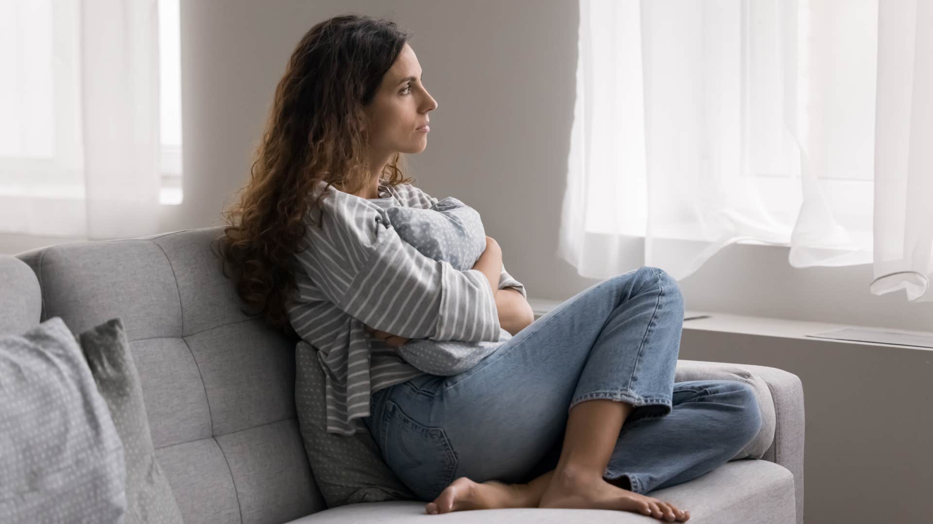 Serious young woman thinking on problem while sitting on couch at home