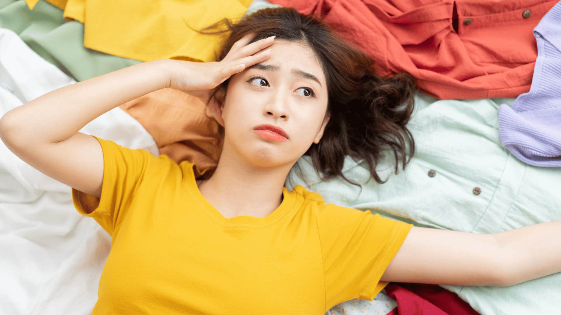 woman laying in a mess of clothing