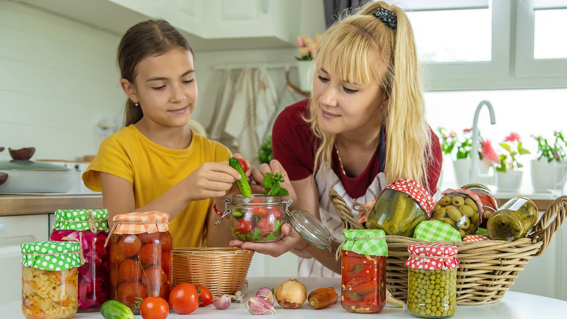 Woman smiling and canning fruits with her daughter