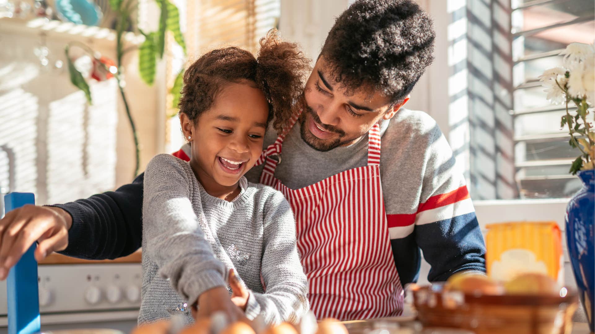 Young girl smiling and cooking with her dad