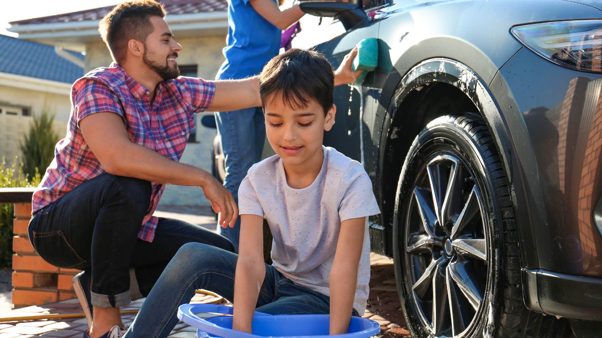 Family smiling and washing their car together