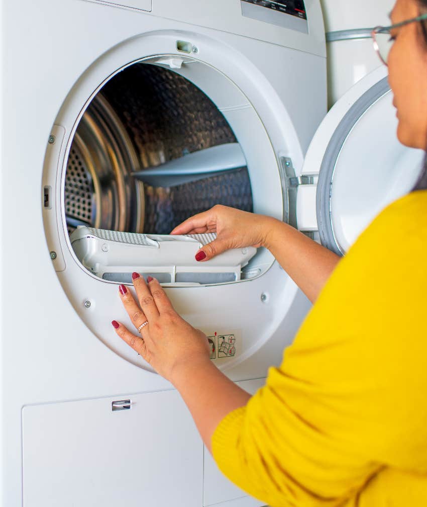 Woman cleaning lint from dryer to avoid fire