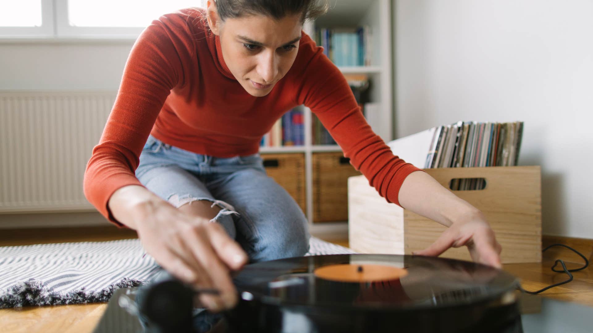 Low angle view of audiophile girl playing favorite LP from her home records collection. 