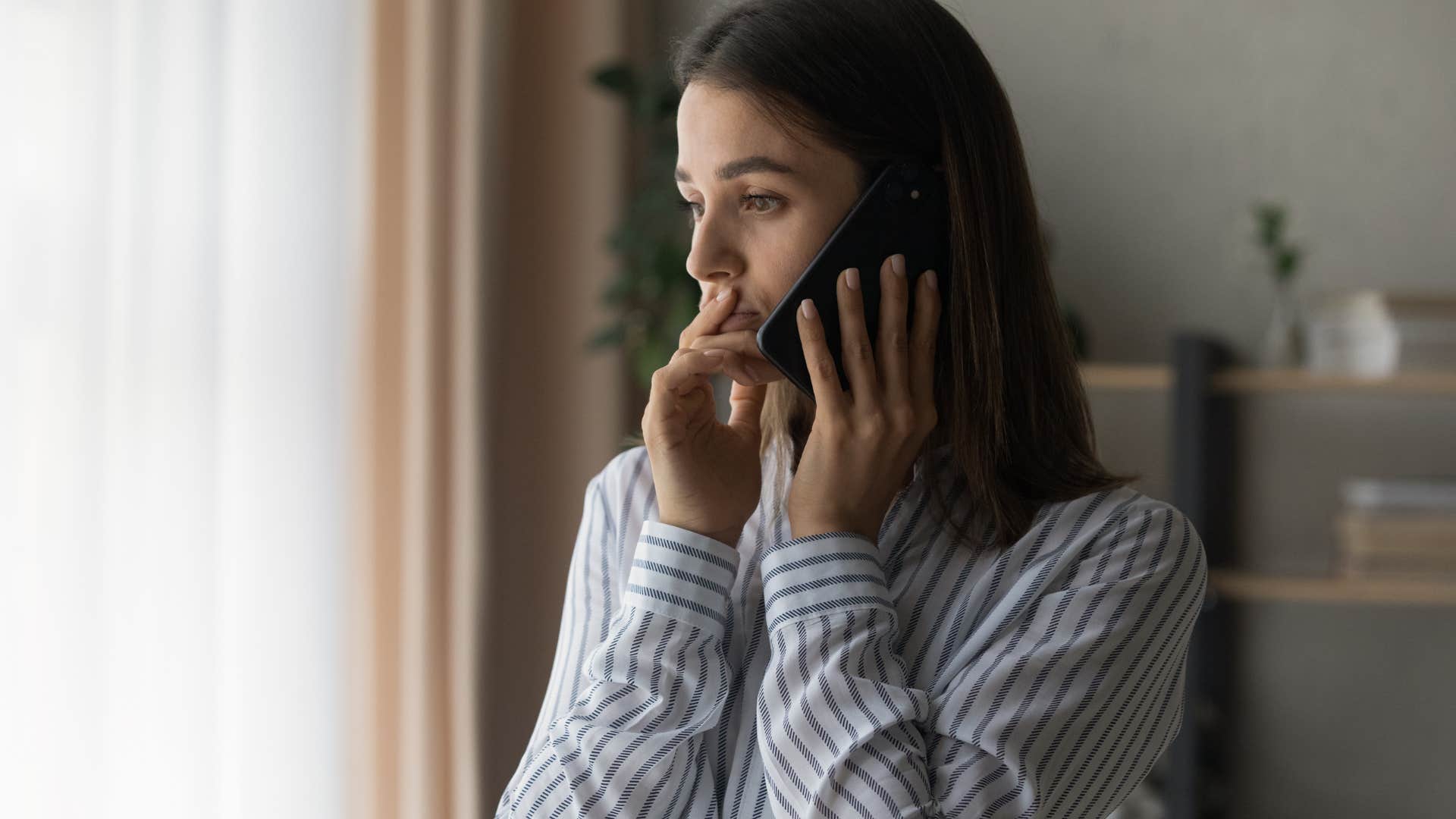 Woman looking anxious talking on her phone.