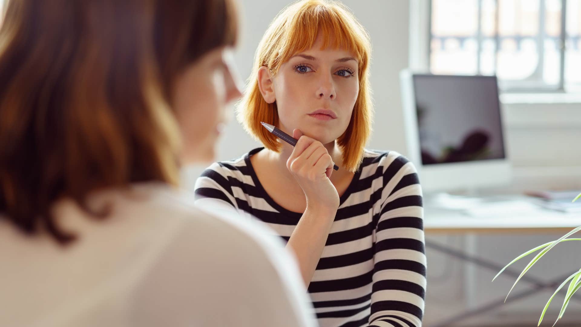 Woman looking annoyed talking to a co-worker.