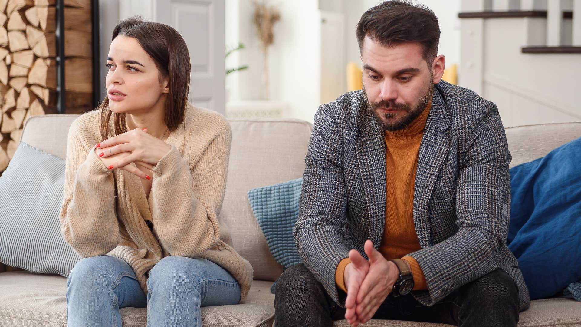 Couple sitting awkwardly next to each other on a couch.