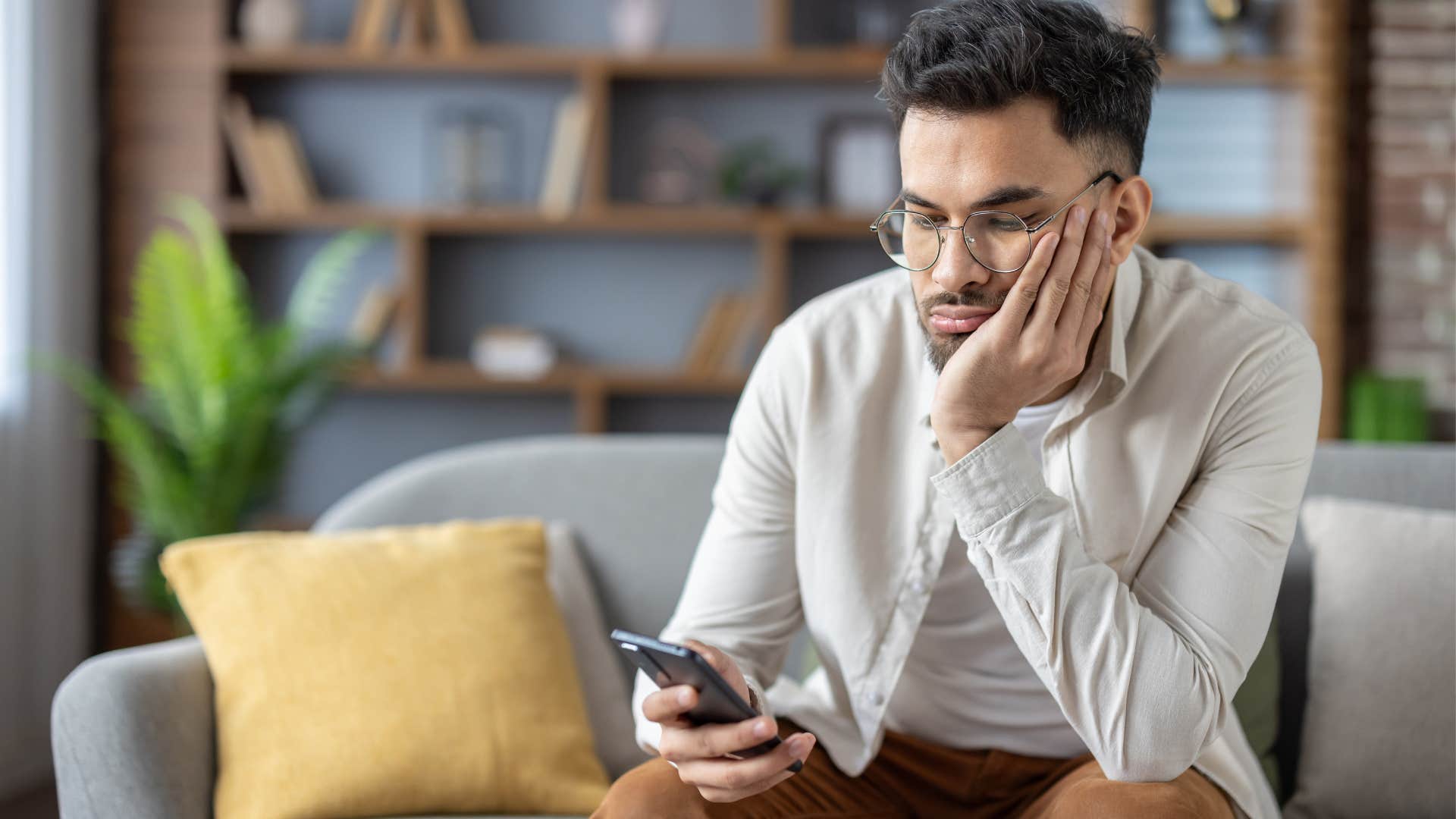 Sad man scrolling on his phone.