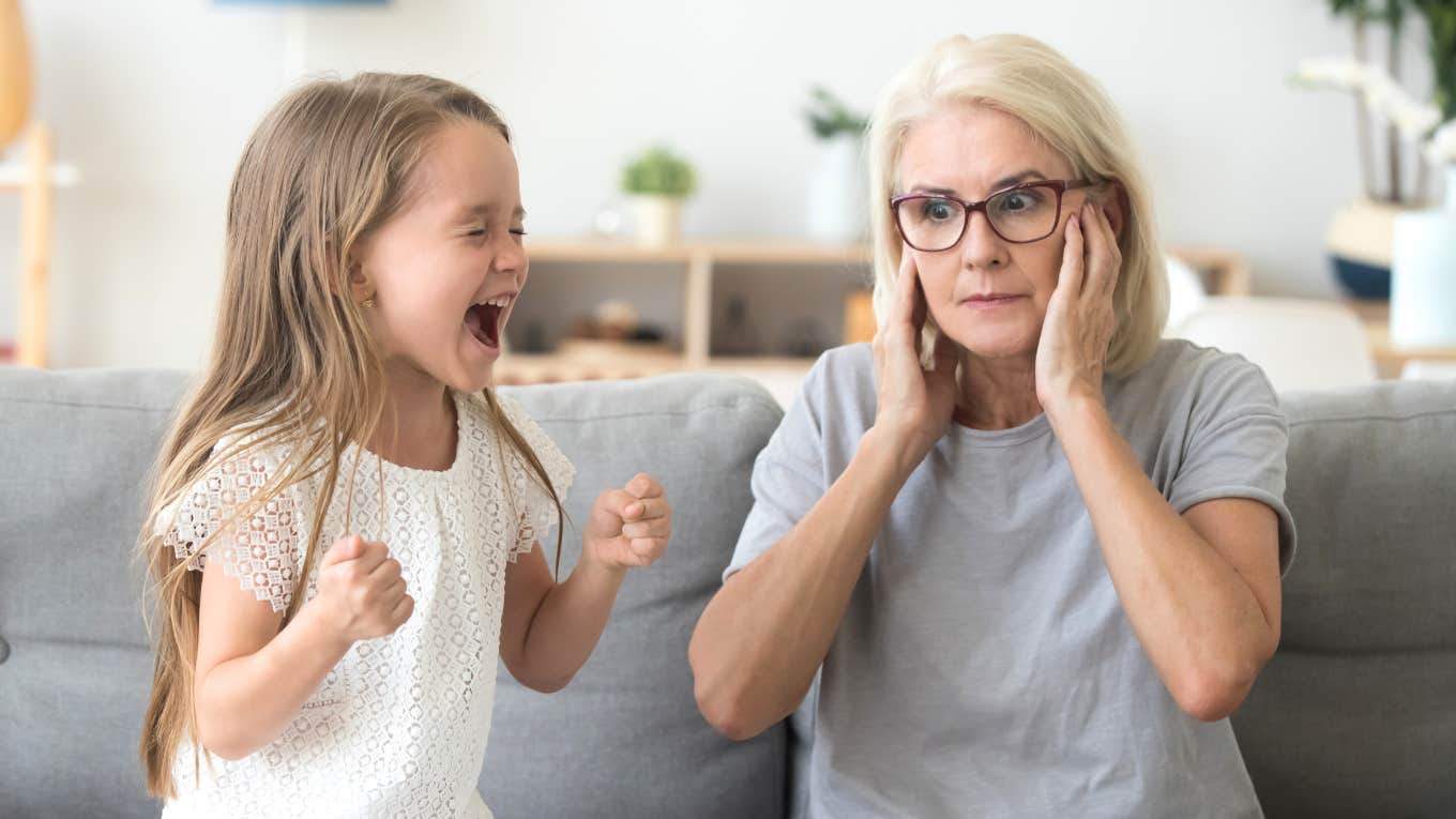 grandmother holding her ears while unruly child screams