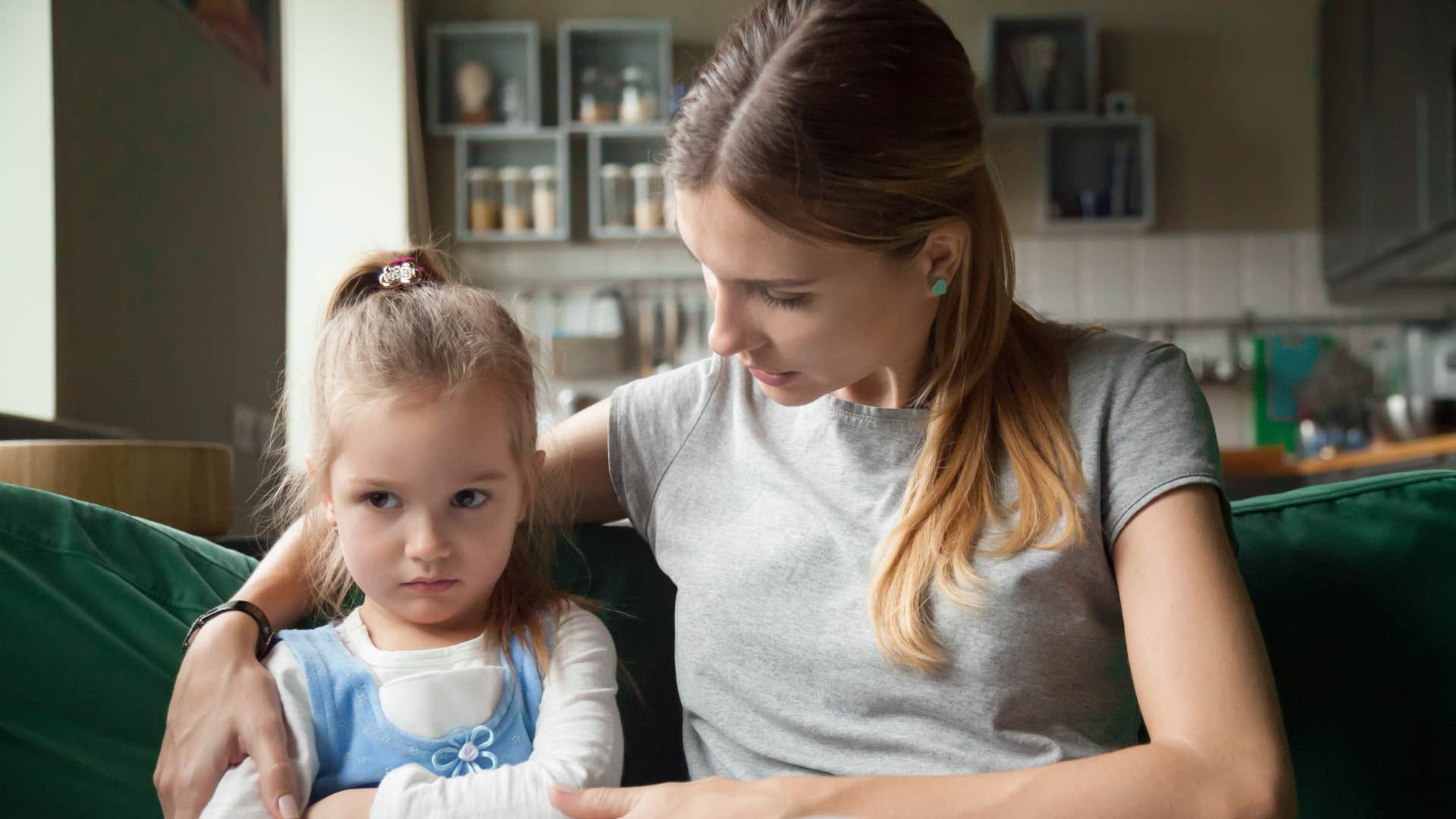 little girl avoid responsibility sitting next to mother