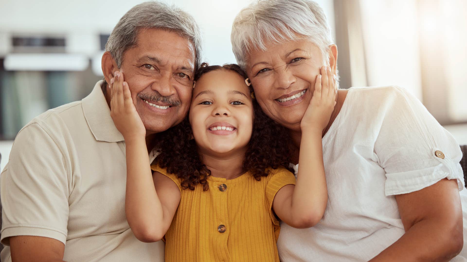 little girl hugging her grandparents' faces