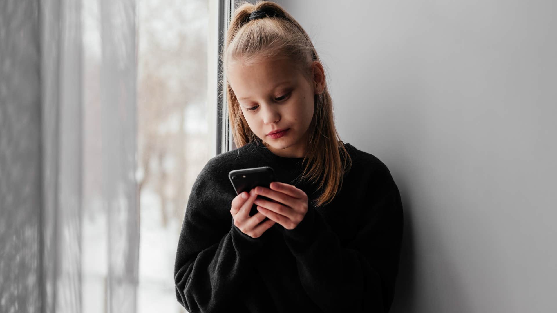 Young girl texting on her phone at home