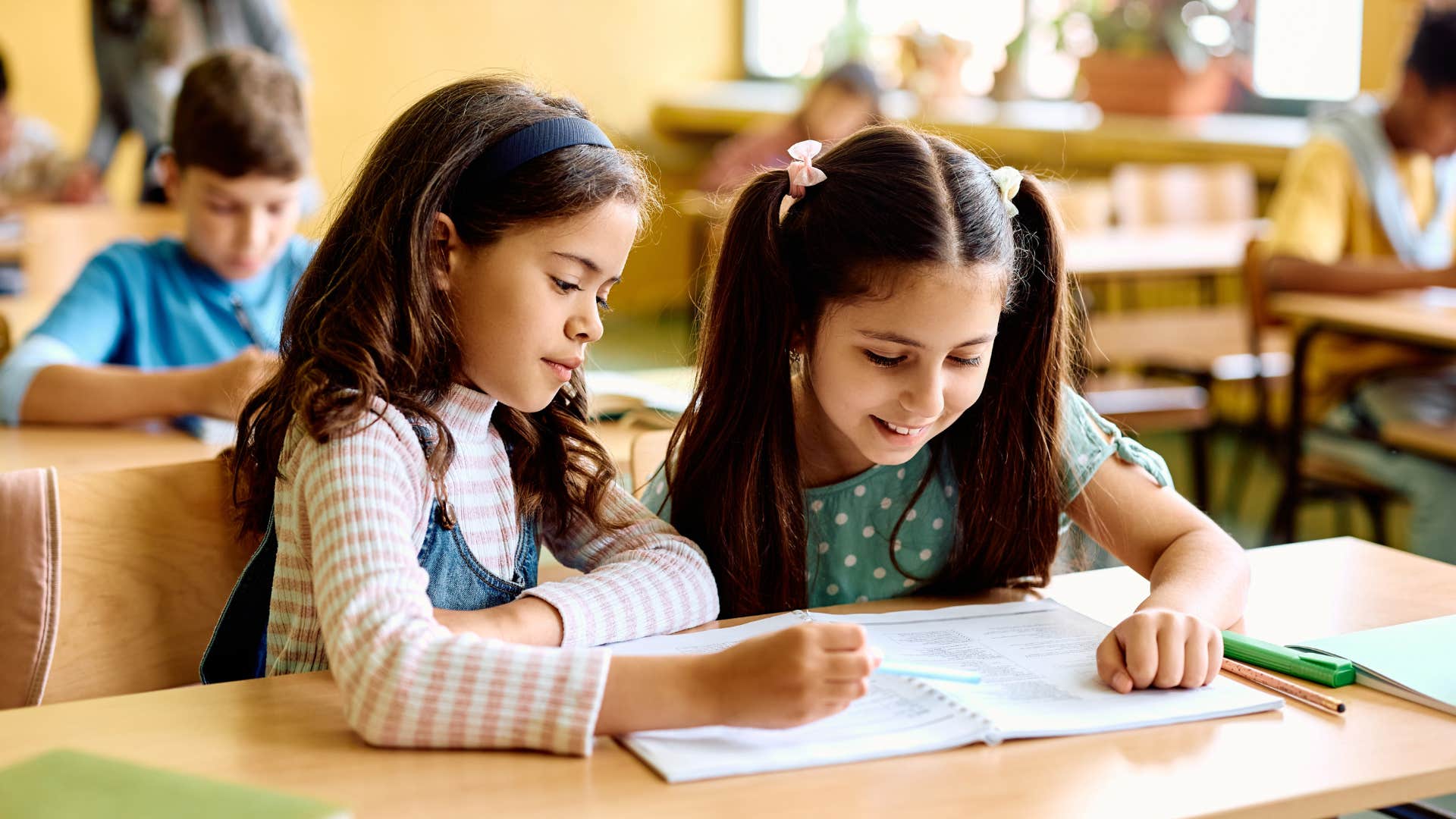 Two young girls reading together at a desk