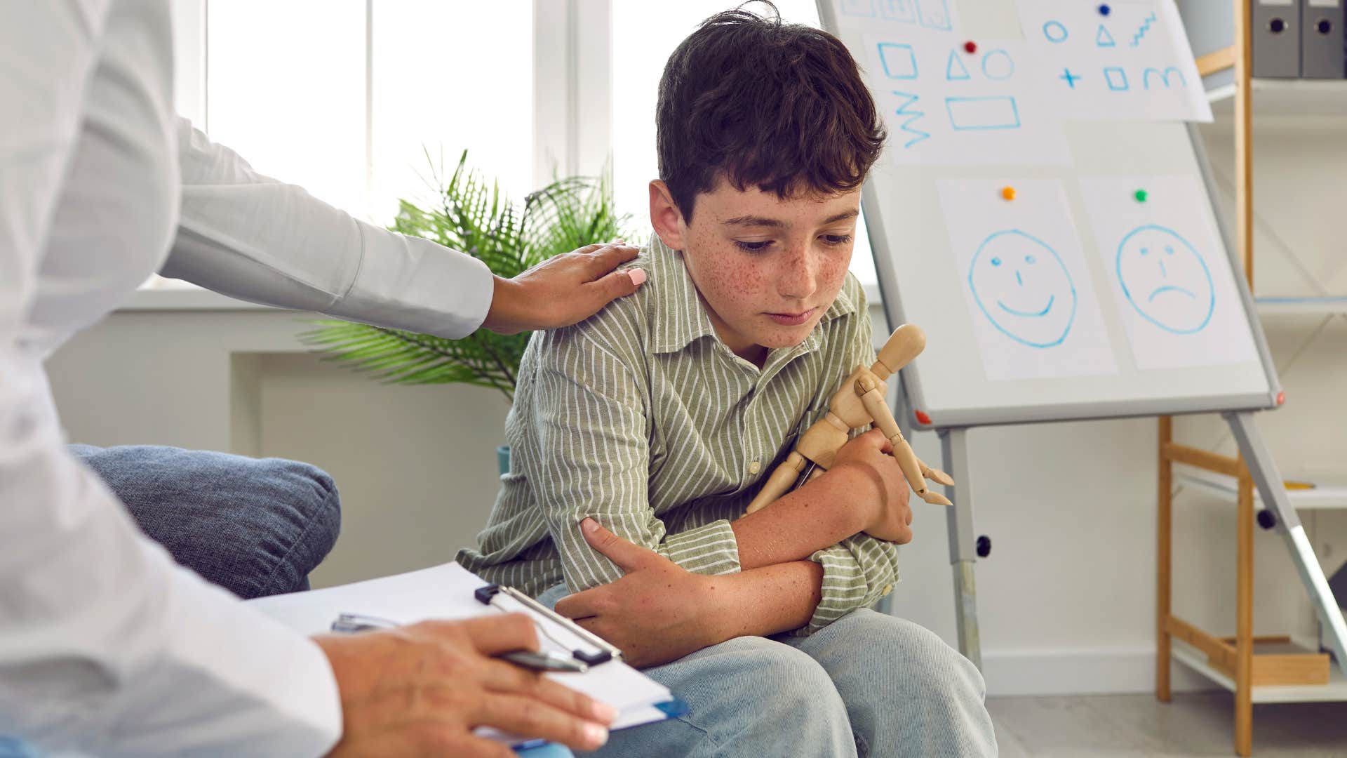 Man comforting a sad young boy with a stuffed animal