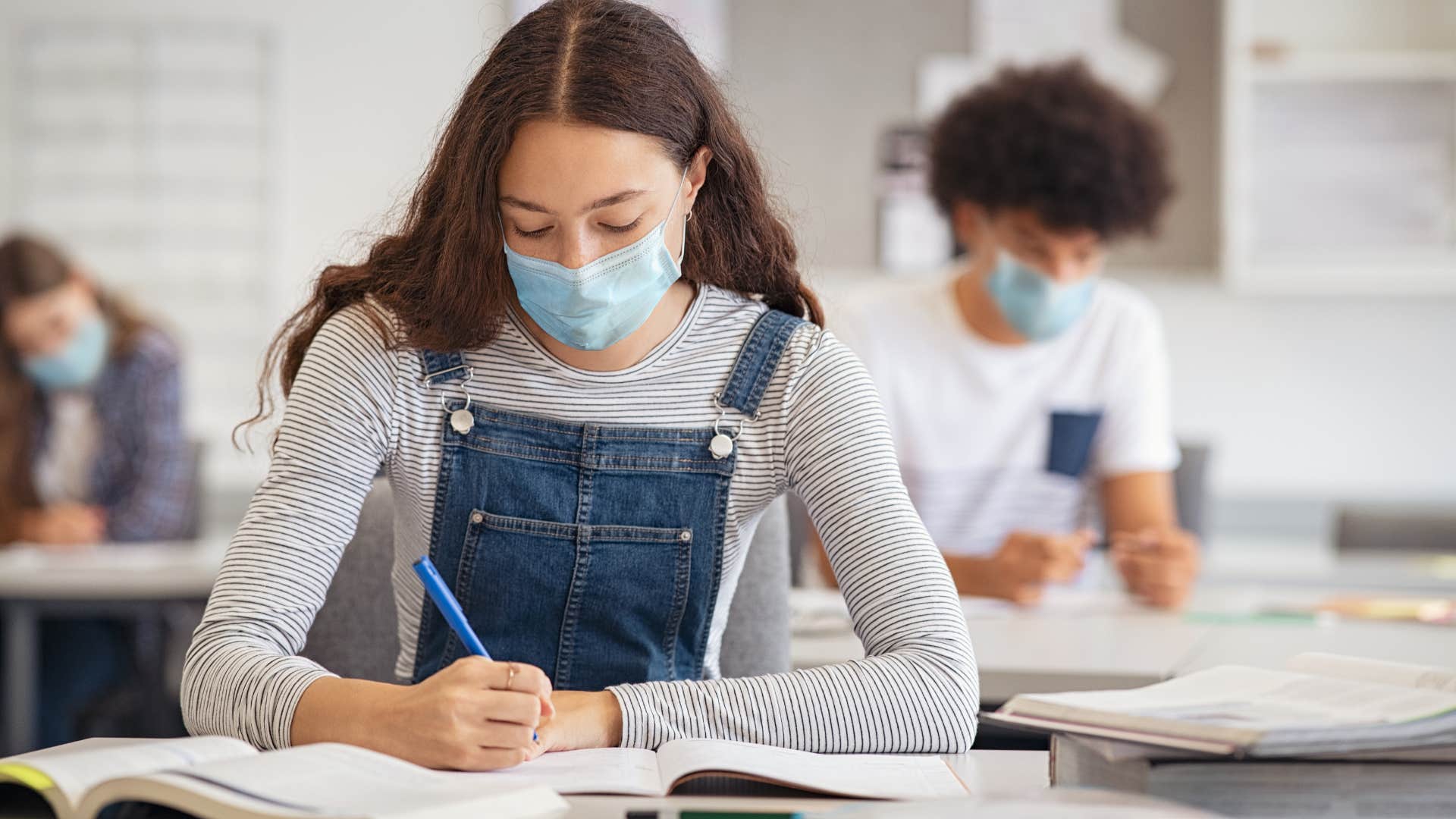 Teenage girl taking a test at her desk in school