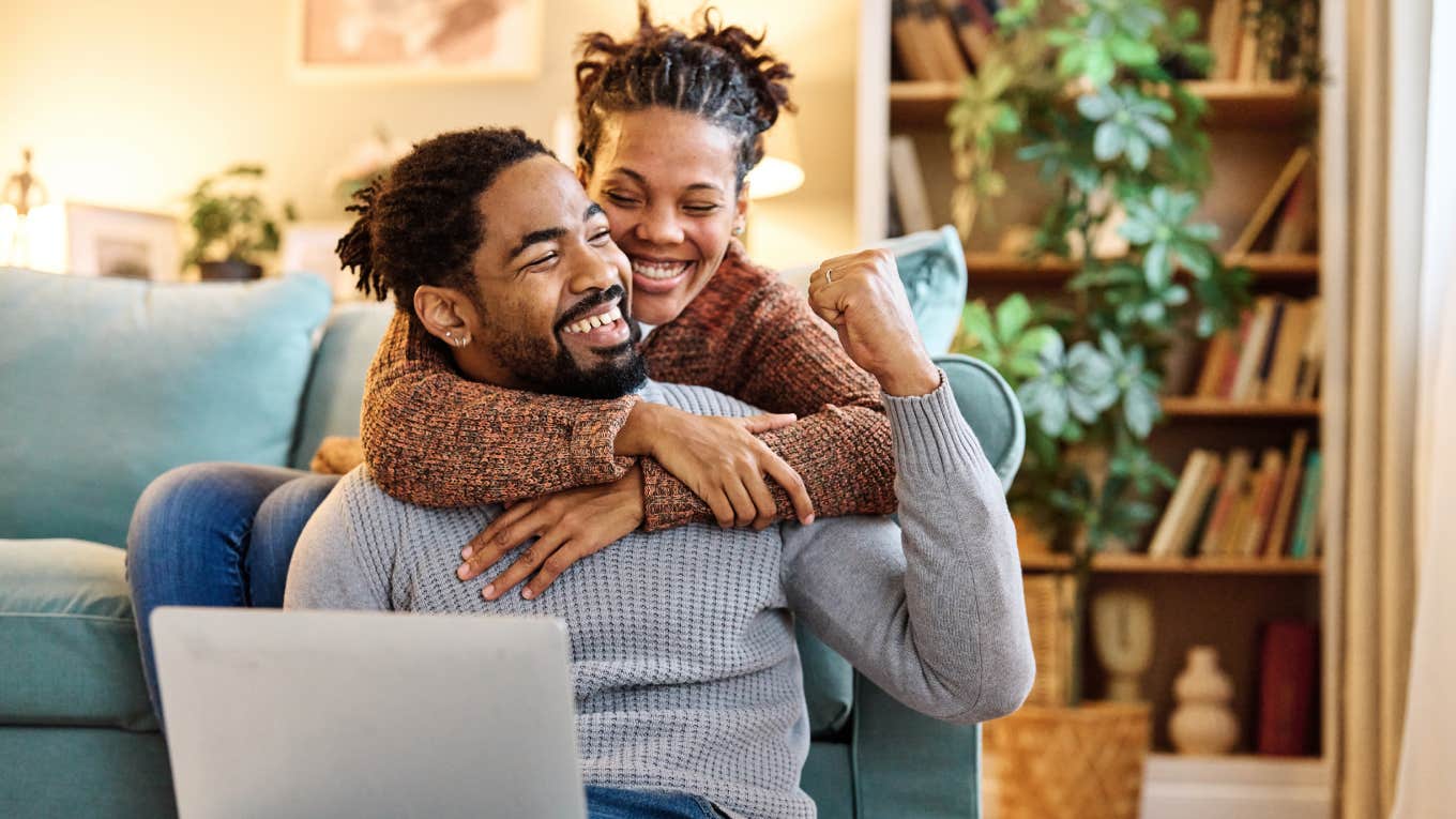 Young happy black couple having fun using a laptop at home