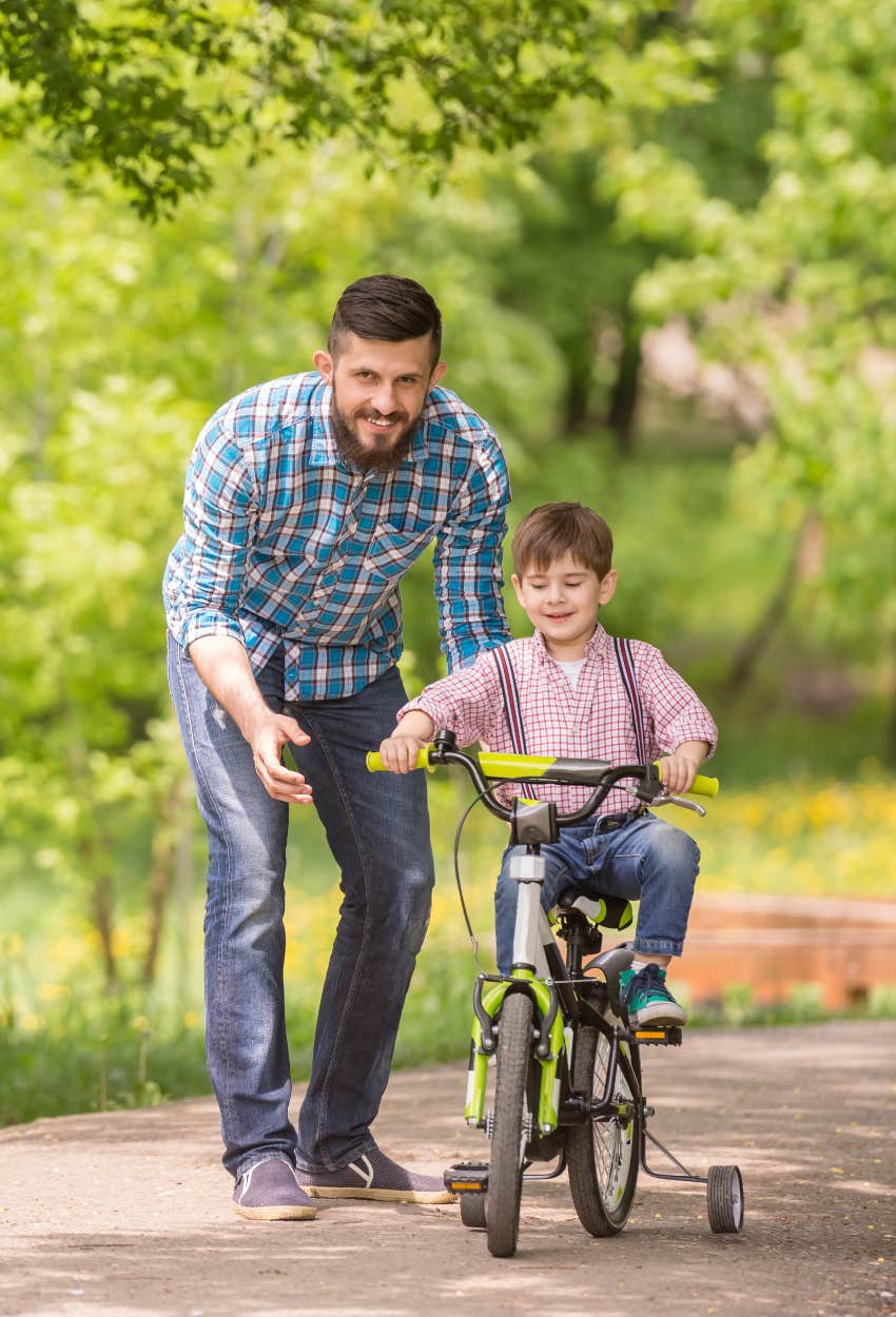 Dad helping his son ride his bike