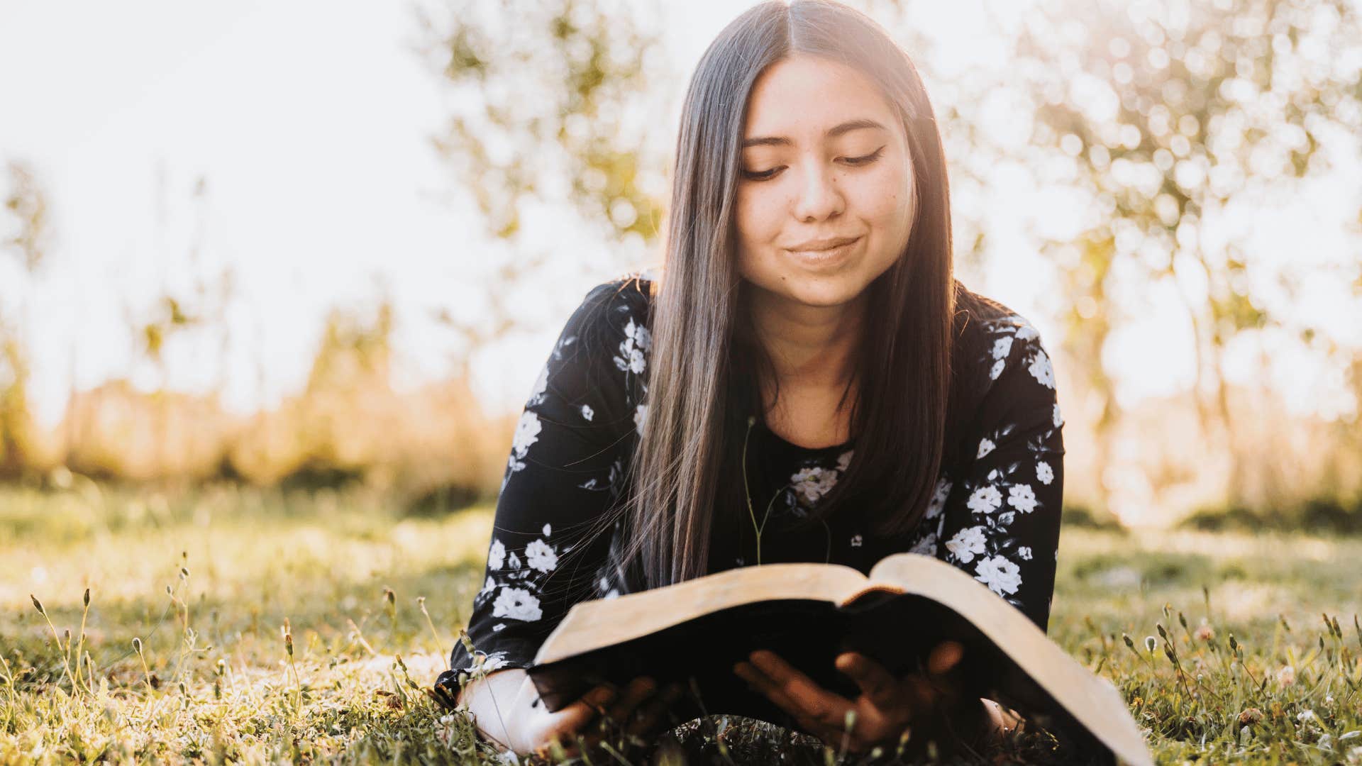 young woman reading a book outside