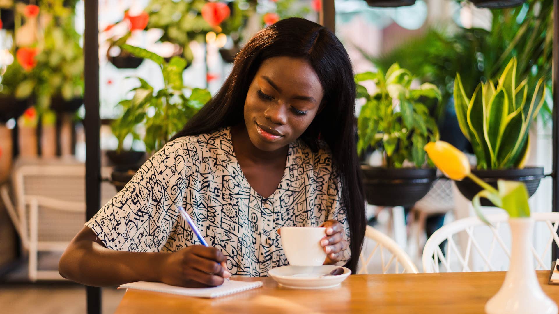 woman sitting in cafe writing down list