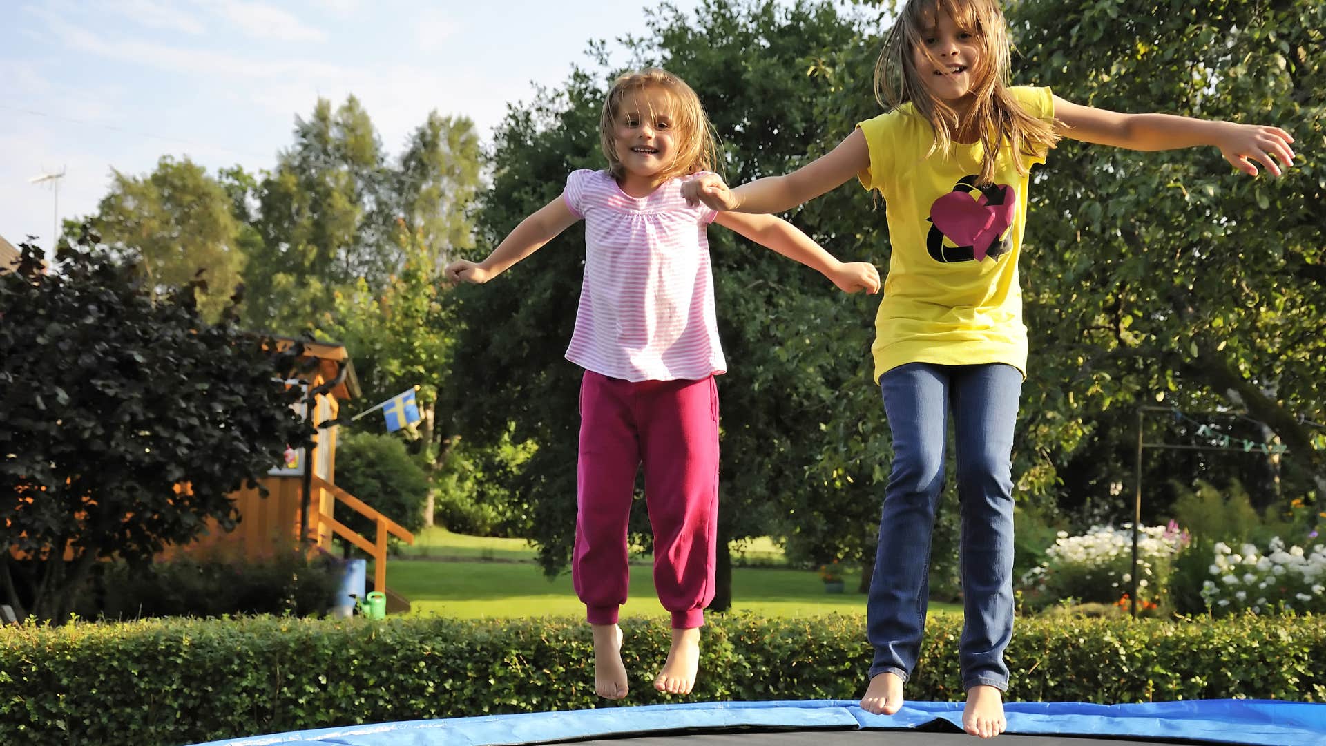 two little girls jumping on a backyard trampoline