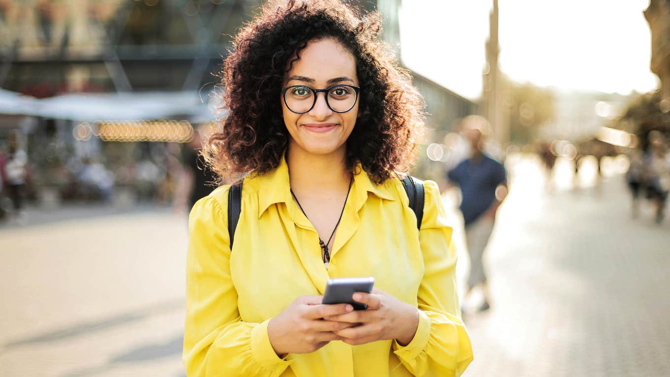 Woman smiling while making money on app on phone. 