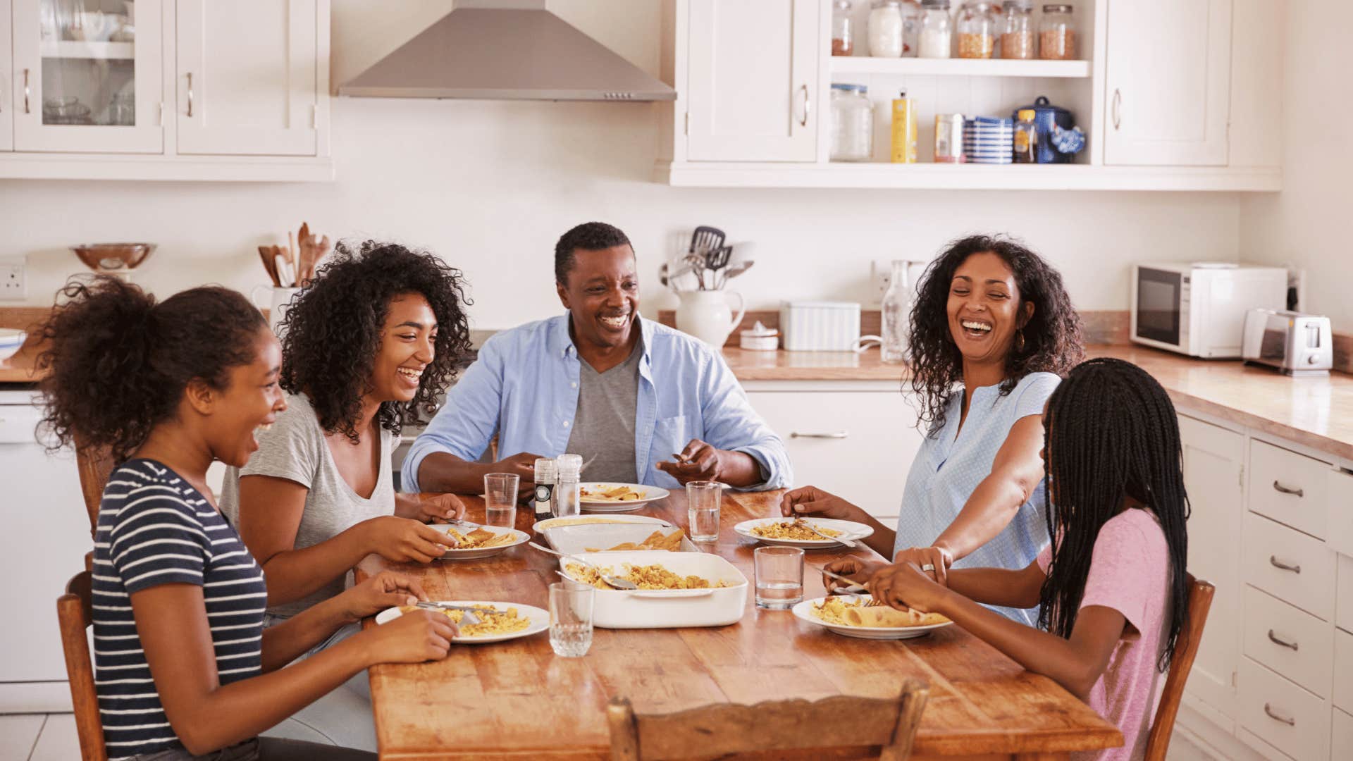 Family has dinner in kitchen while talking together