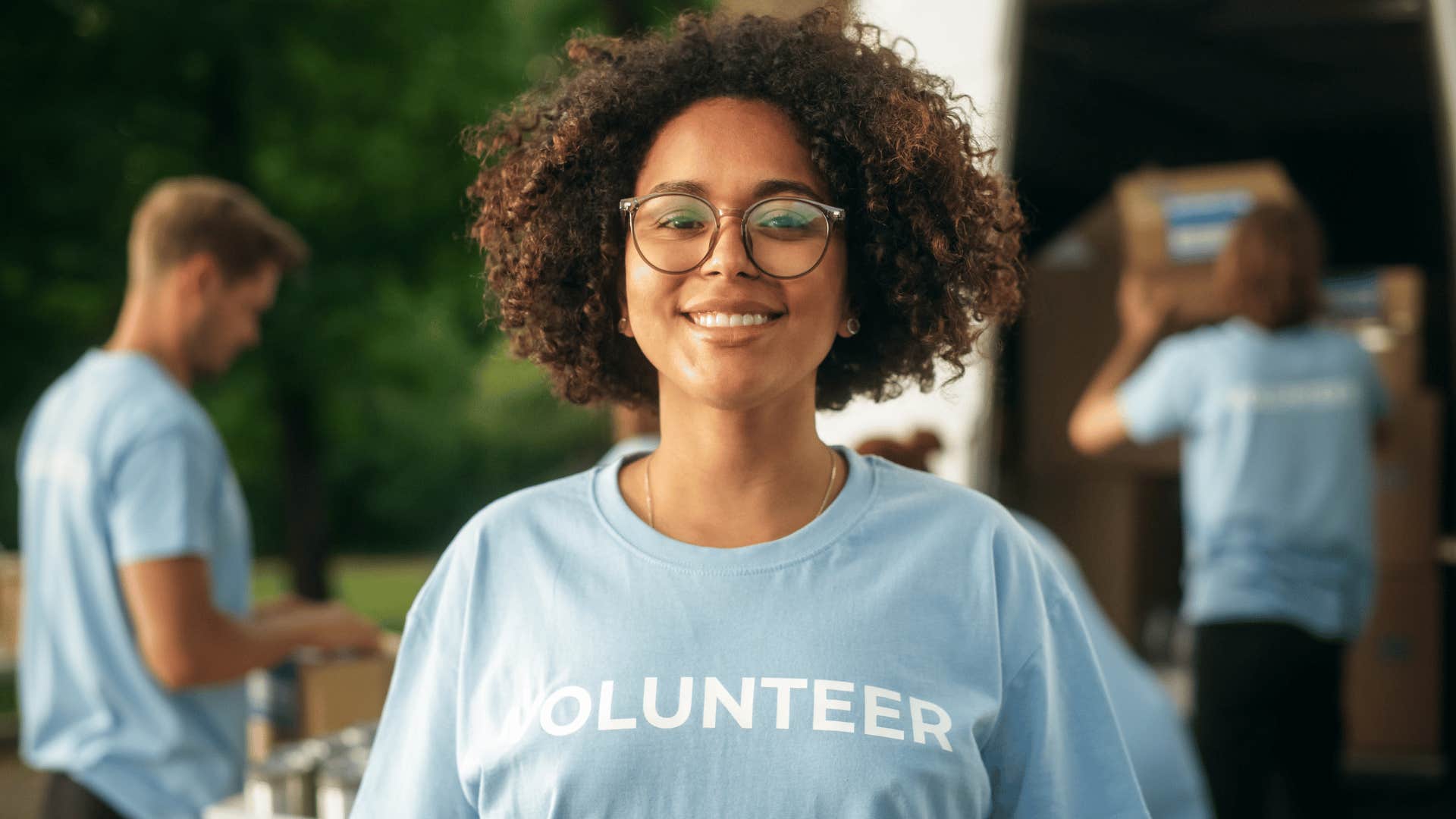 woman wearing volunteer shirt and smiling at the camera 