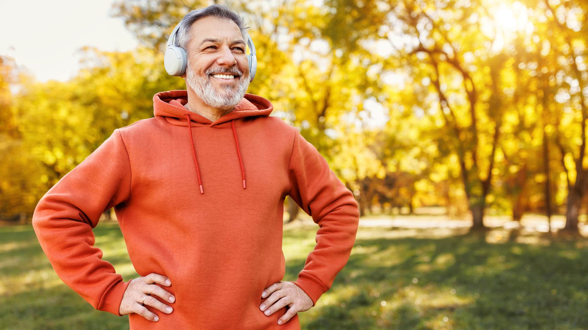 Man smiling outside with headphones on.