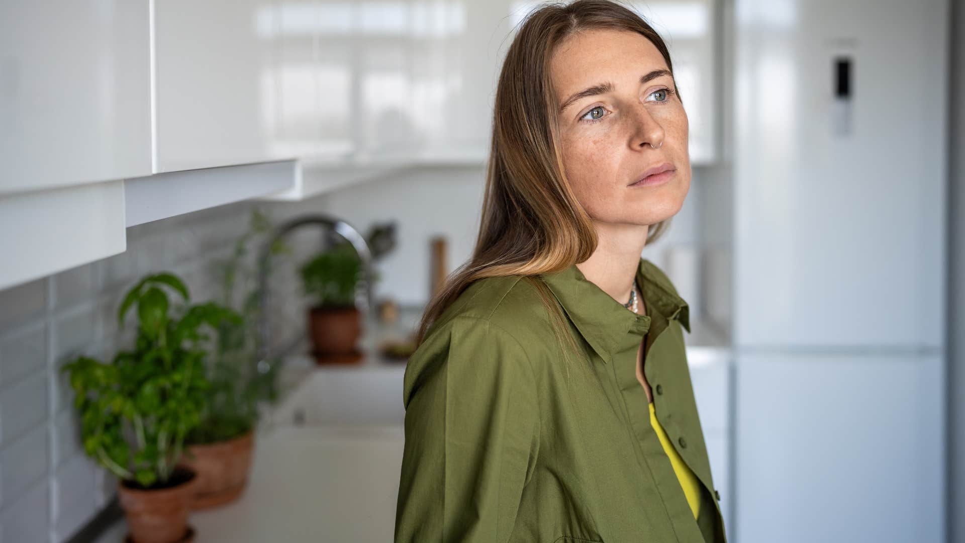 Sad woman leaning on the counter in her kitchen.