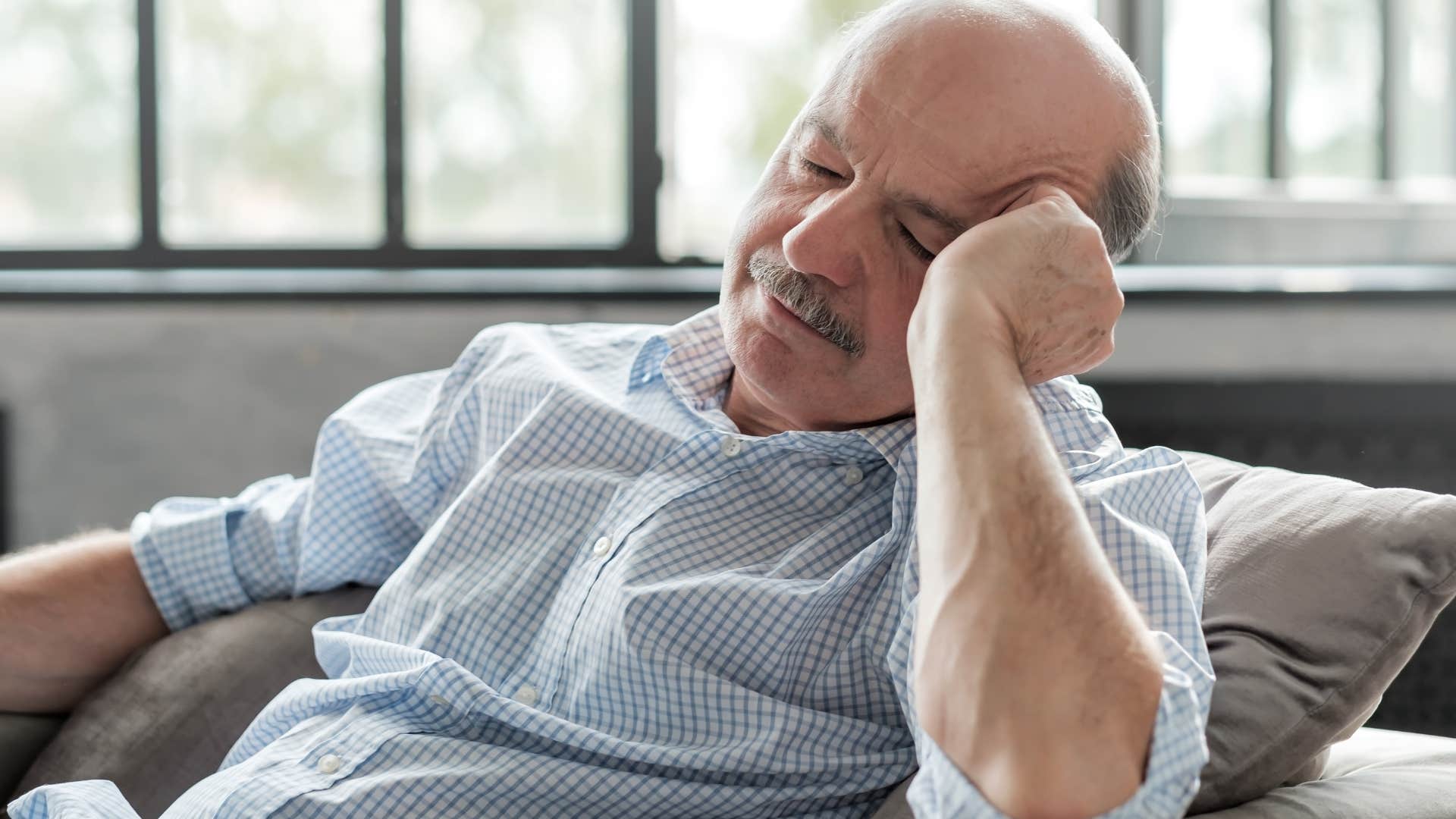 Older man sleeping on the couch.