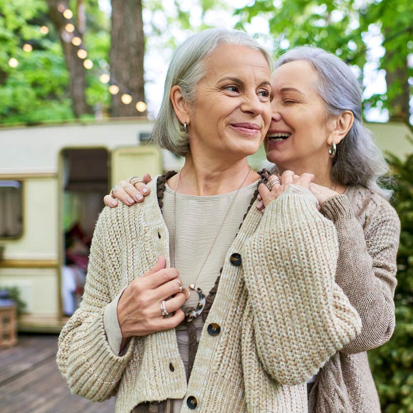 Retired couple embrace outside travel trailer