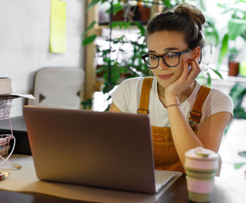 Young female worker in glasses using laptop