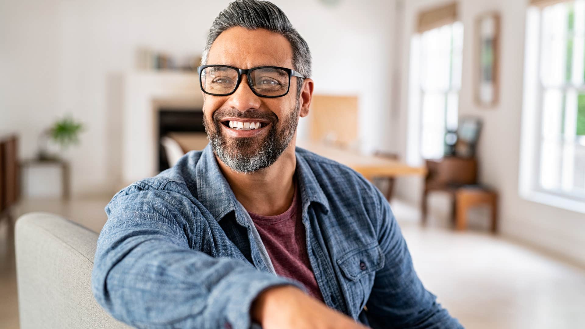 Man smiling while sitting on his couch.