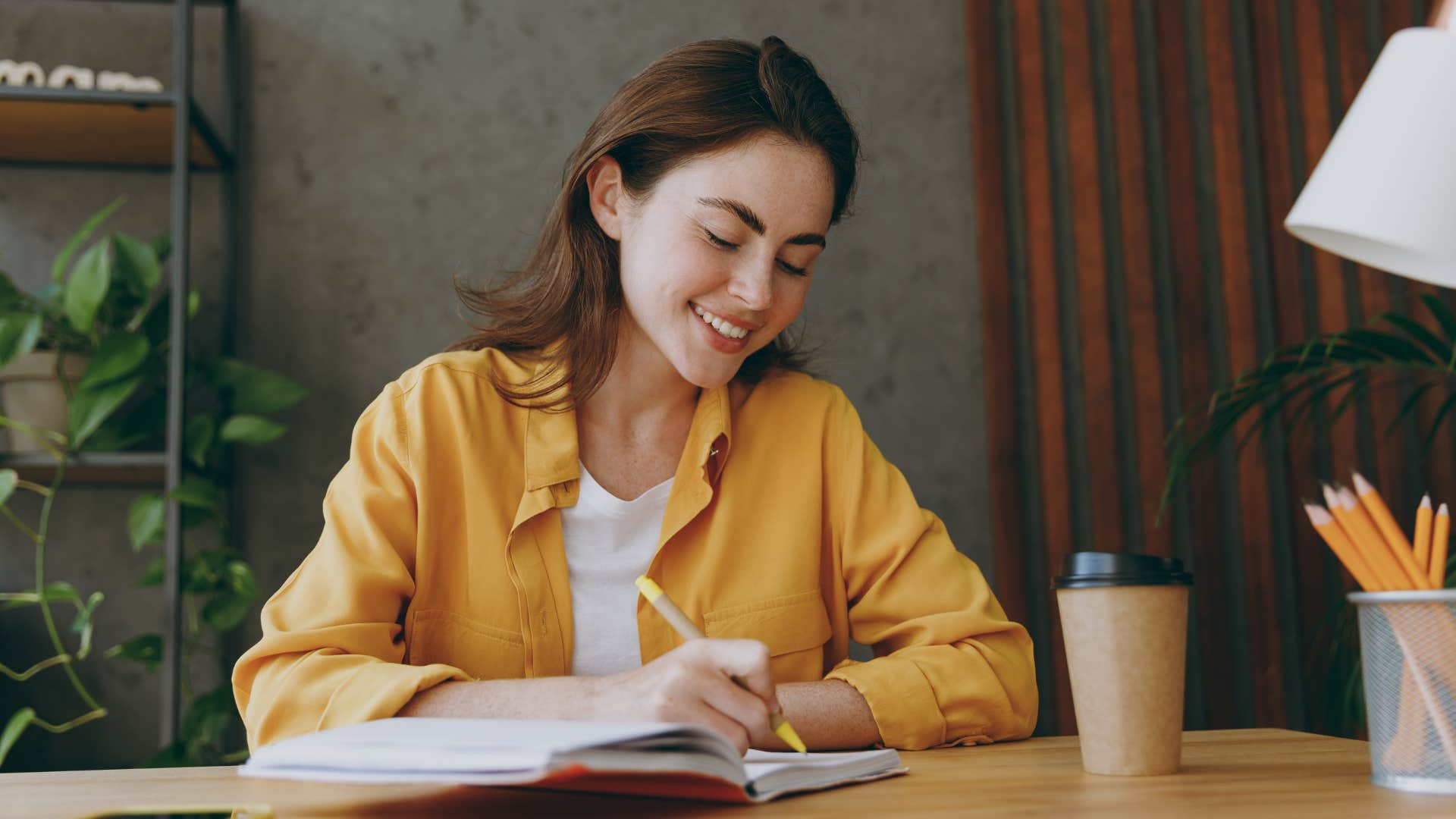 Woman smiling and writing in her journal. 